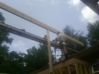 Carpenter setting a ridge beam over a new addition frame in Rock Spring