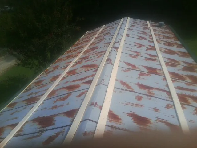Rusted metal roof panels with new wood purlins before replacement — Storm Damage Roof Repair in Rock Spring by Roofing Brothers