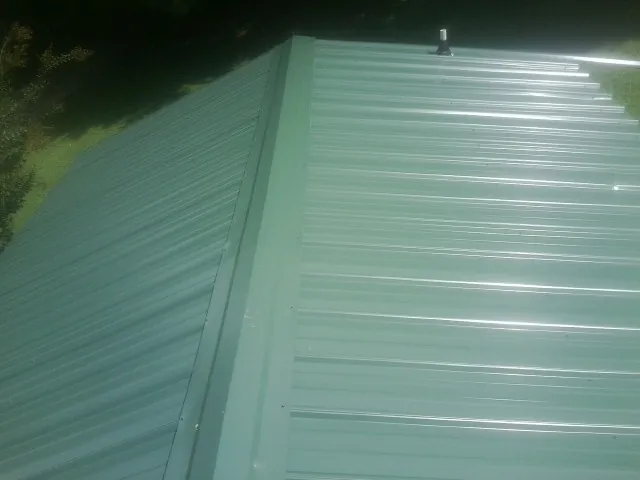 New green metal panels meeting at the ridge of a roof — Flat Roof Repair work by our crew in Rock Spring