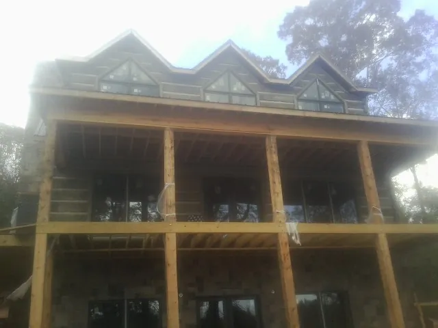 Dormers and porch framing on a large log home under construction — Roof Coating work by our crew in Rock Spring