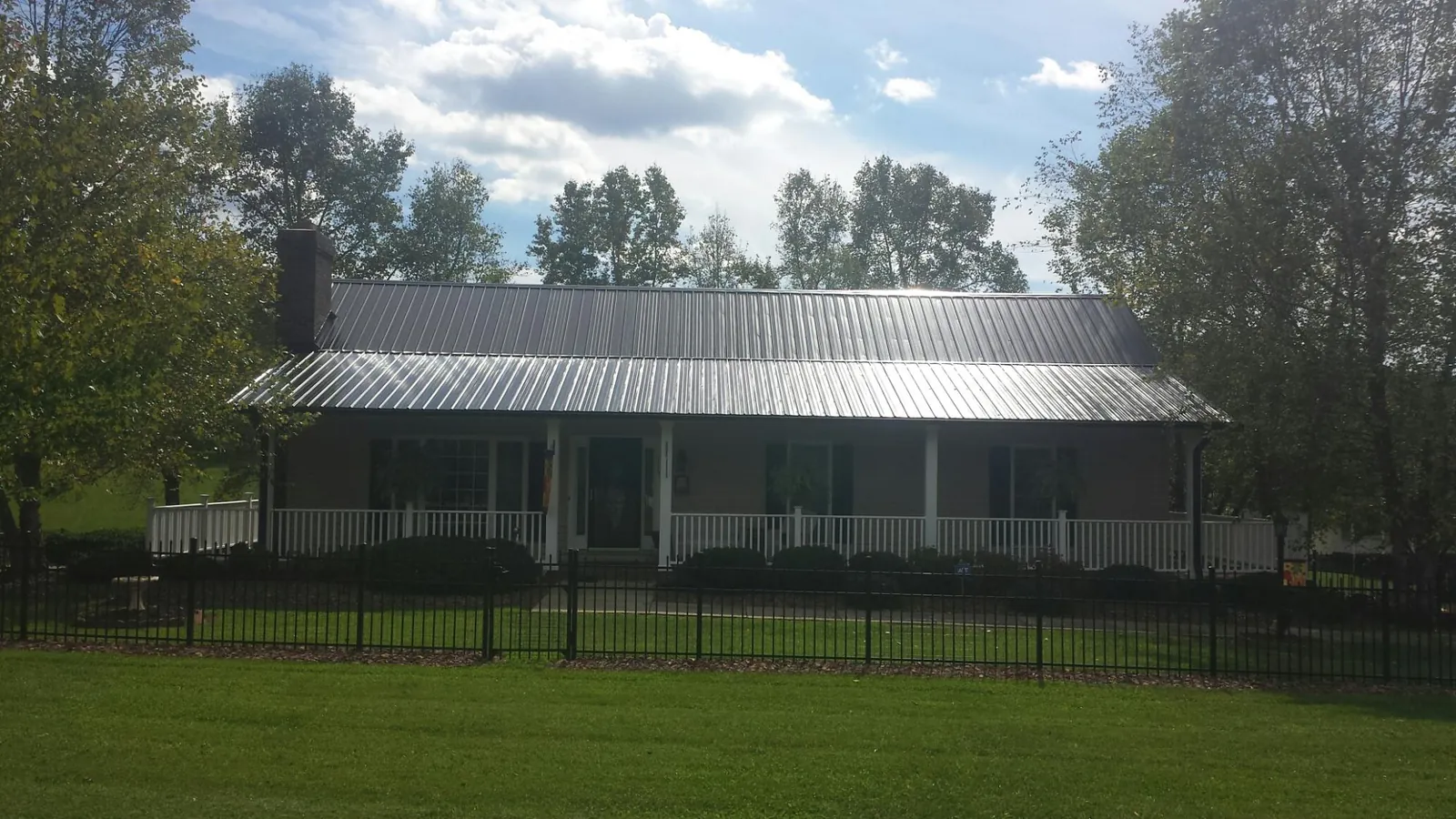 Gray metal roof on a brick ranch with a full width front porch — Gutter Guard Installation work by our crew in Rock Spring