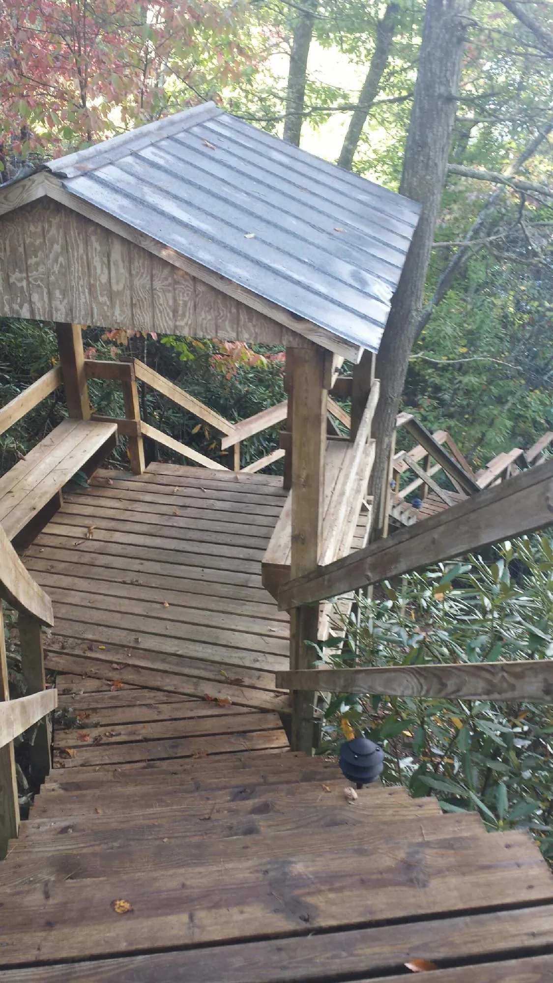 Metal roofed shelter over wooden steps on a wooded walkway — Skylight Repair & Installation work by our crew in Rock Spring