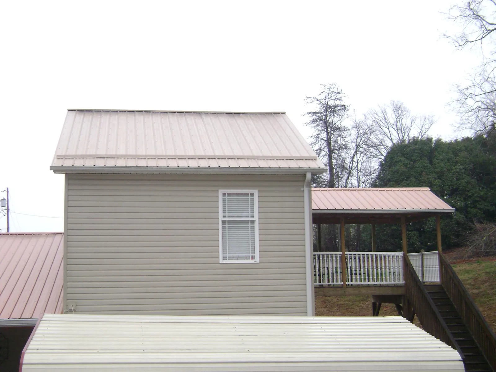 Tan metal roofs on a two story addition and attached porch, from a Roof Replacement job in Rock Spring