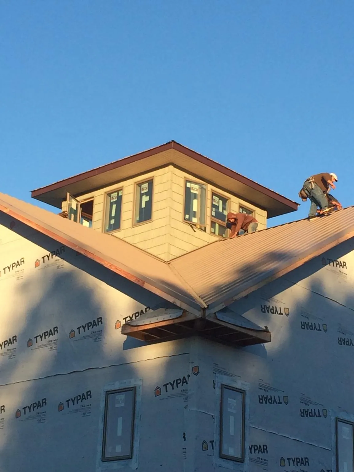 Roofers working around a rooftop cupola on a new metal roof at sunset — Roof Waterproofing in Rock Spring by Roofing Brothers
